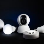 A collection of smart home devices, including bulbs and security cameras, on a dark background.