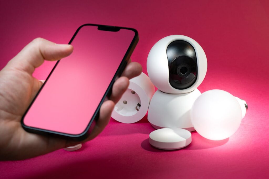 pexels photo 22610381 Smart home setup including smartphone and security devices against a vibrant pink background.