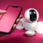 hero-img-02 Smart home setup including smartphone and security devices against a vibrant pink background.